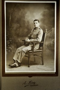 Mounted, sepia-tinted photograph portrait of Elphick seated in uniform with a corporal's stripes. Photographed by A. Hing of Hong Kong